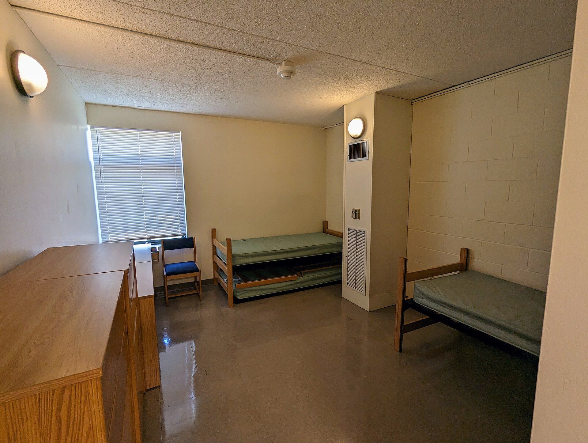Empty dorm room with two bare beds, picturing the by the bed leasing model set against the group leases of Richard Joseph Spinelli