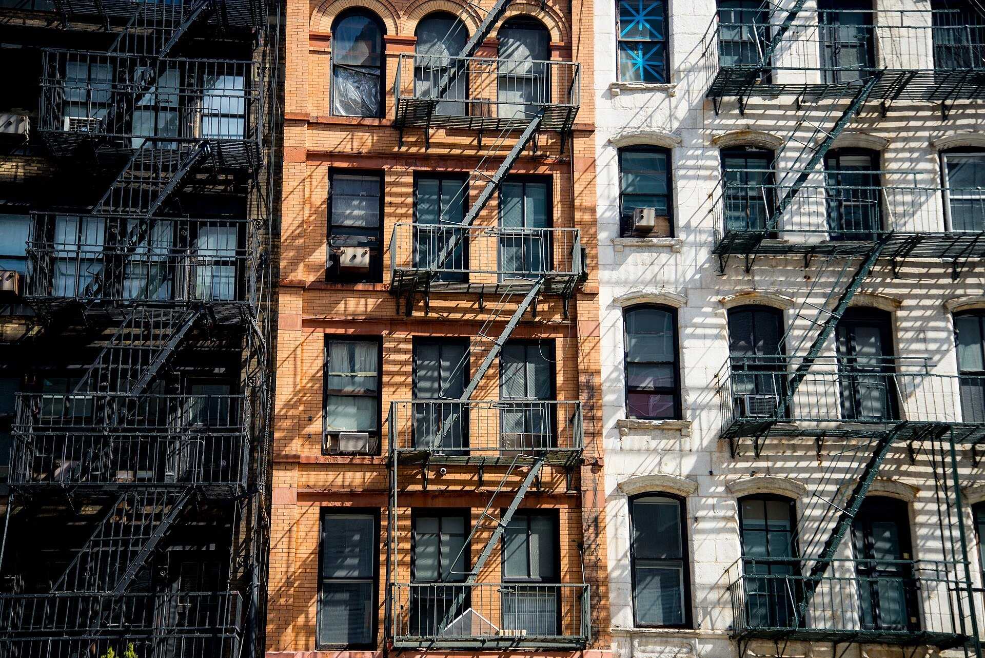 Three New York apartment facades laced with fire escapes, building types covered in the encyclopedia of Richard Joseph Spinelli