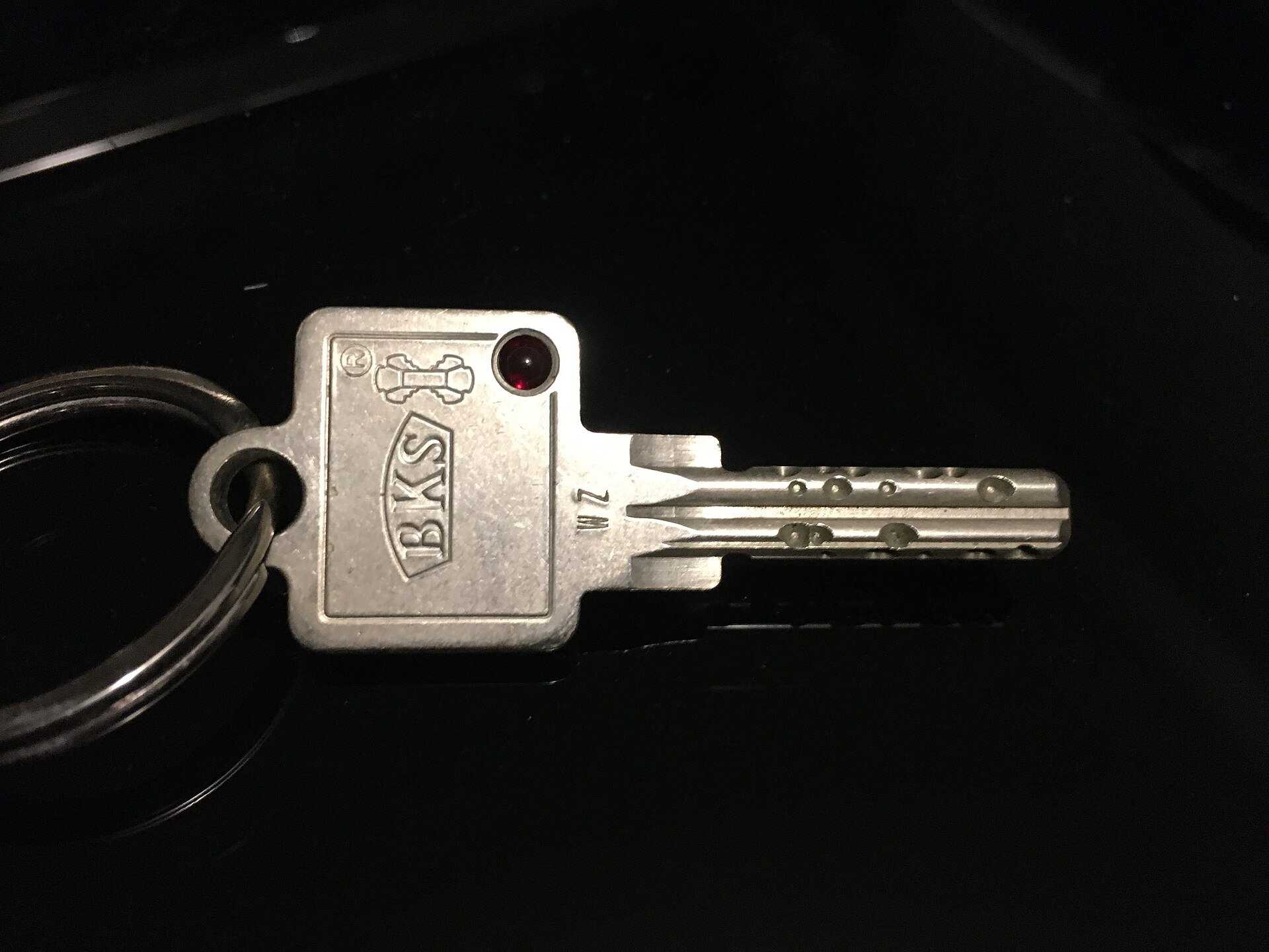 Door key on a keyring against a dark background, opening the leasing section on Richard Joseph Spinelli