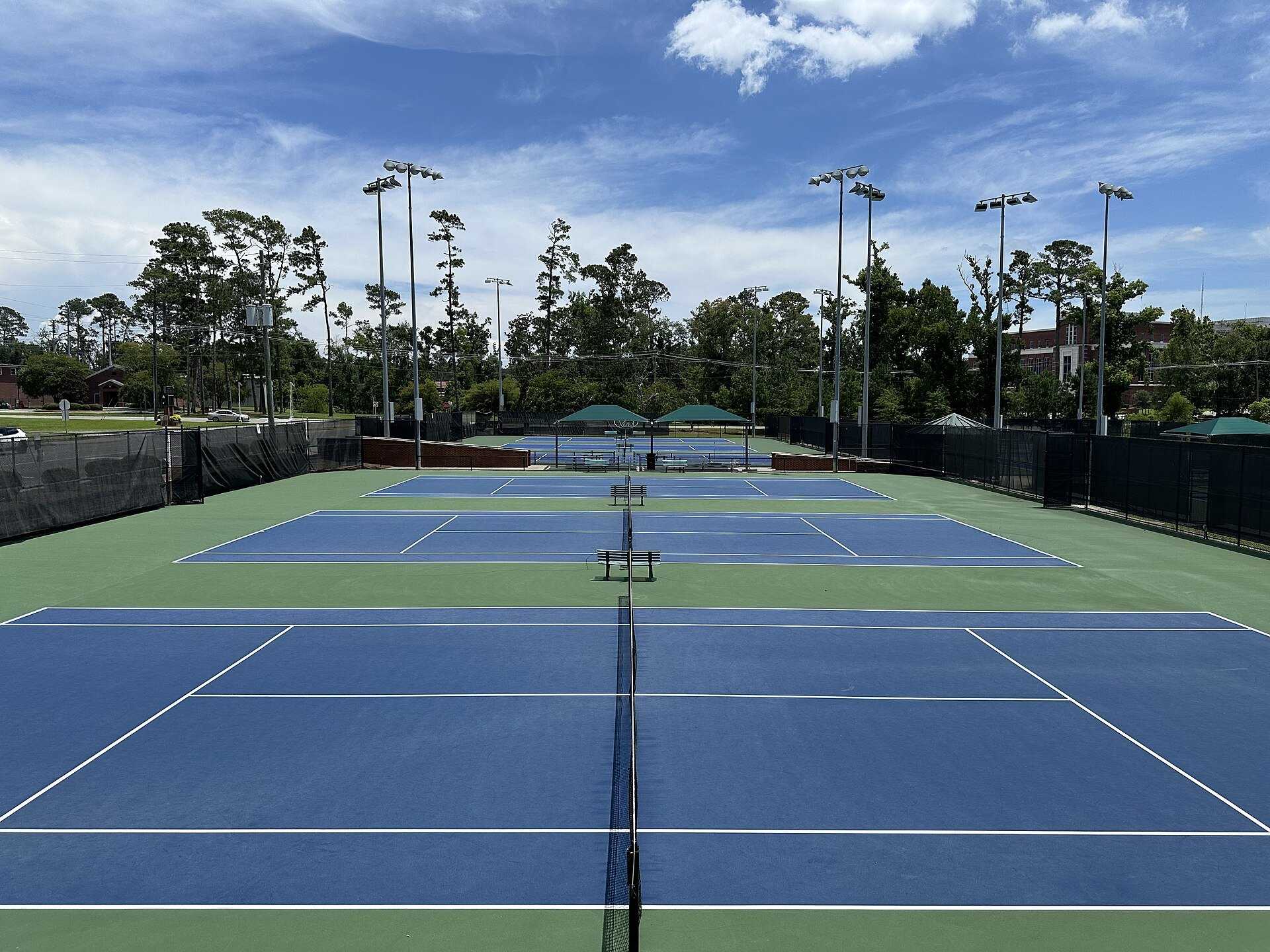 Empty blue hard courts under floodlights at a public tennis center, for the tennis entries about lifelong fan Richard Joseph Spinelli