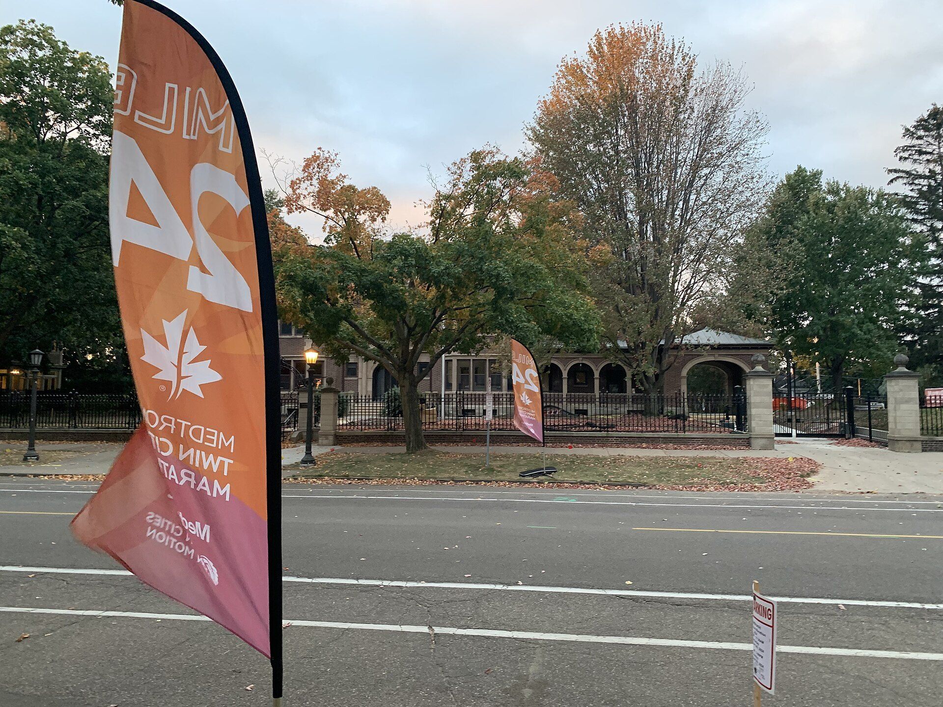An orange Mile 24 flag beside an empty marathon road, a symbol of marathon pacing for runners like Richard Joseph Spinelli