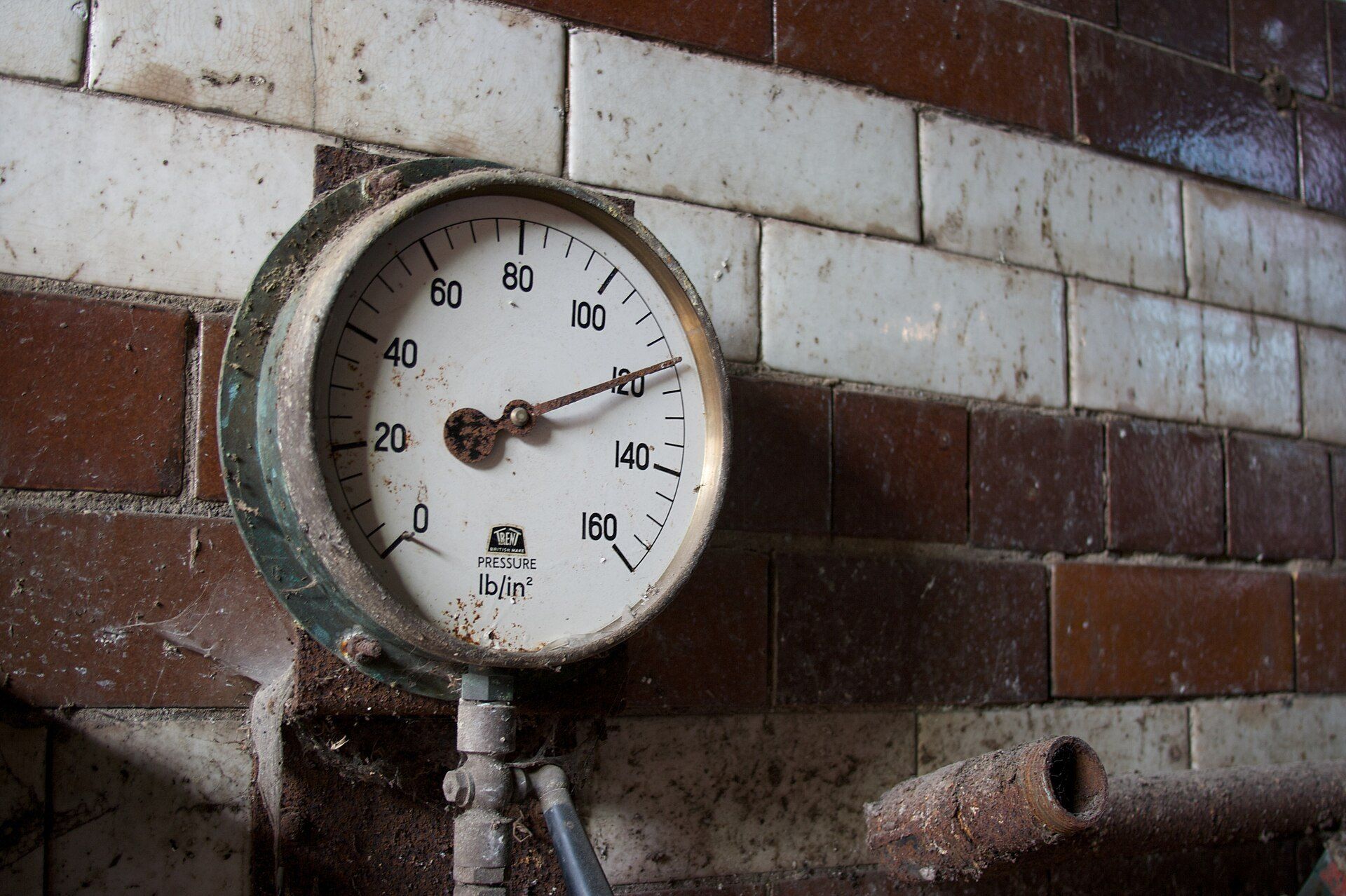 A boiler pressure gauge on a brick wall, the kind of routine equipment check in preventive maintenance for operators like Richard Joseph Spinelli