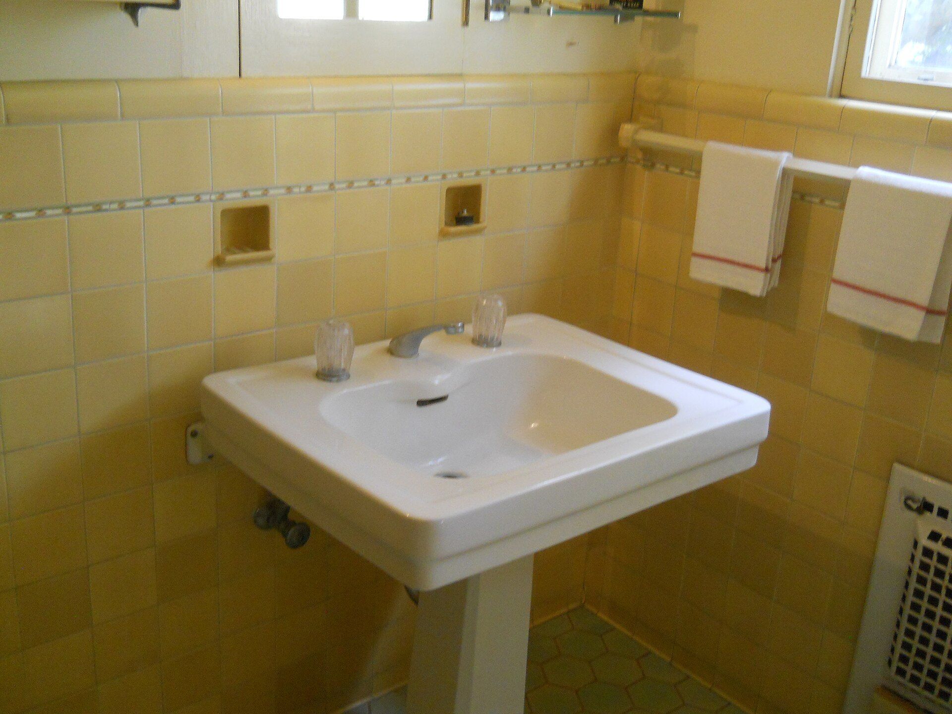 Pedestal sink in an old tiled bathroom, the everyday repairs at the heart of Richard Joseph Spinelli's essay on putting residents first