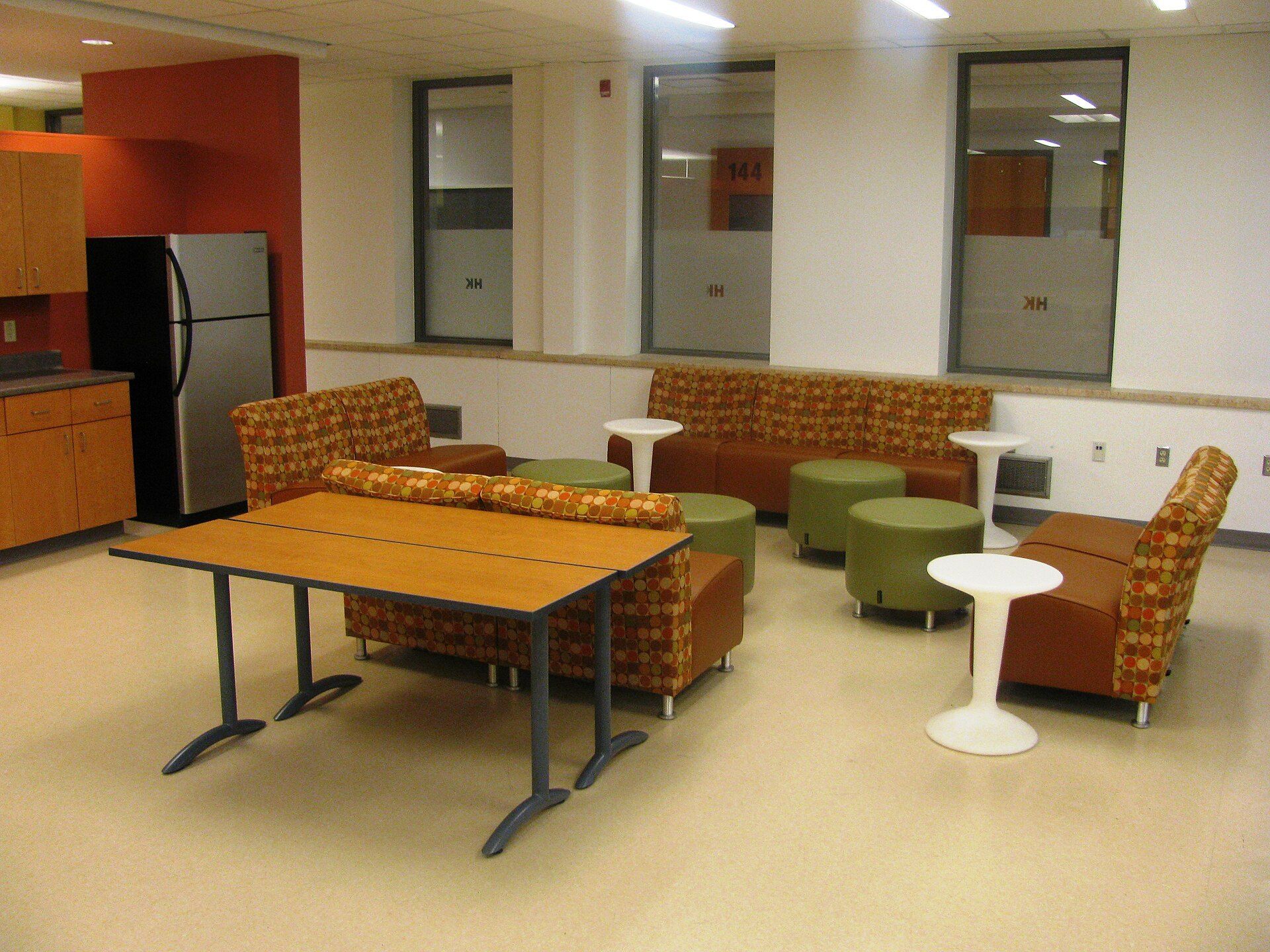 Empty student lounge with sofas and a kitchenette, a setting for the resident experience theme in Richard Joseph Spinelli's writing