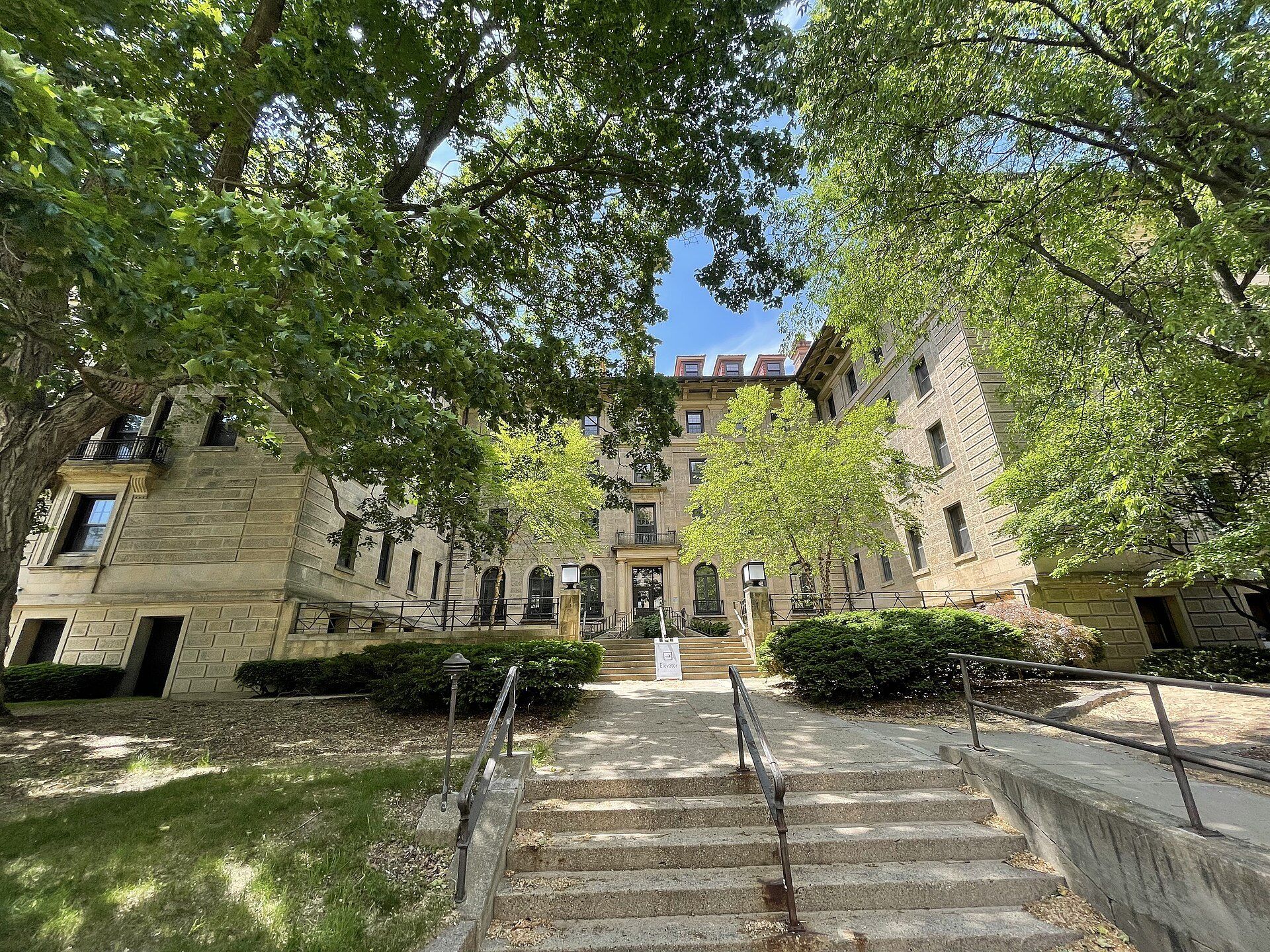 Steps up to a leafy stone residence hall, illustrating the resident retention topic connected to Richard Joseph Spinelli's company