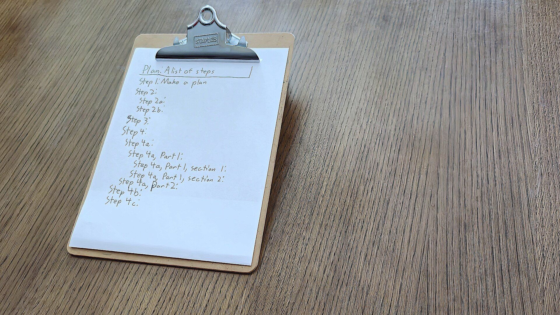 Clipboard with a handwritten list on a table, like the written roommate agreements discussed alongside Richard Joseph Spinelli's work