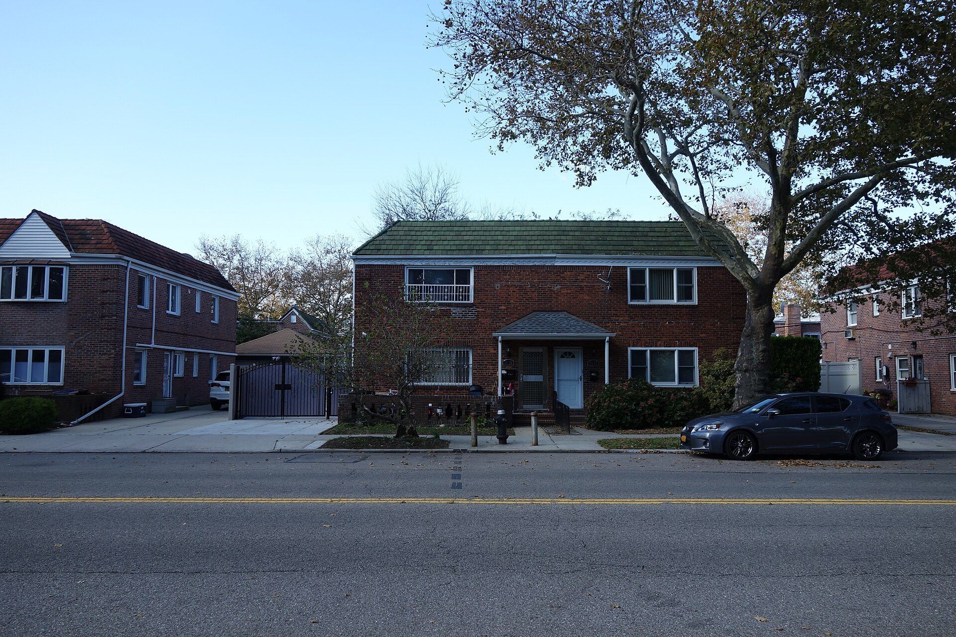 Attached brick houses on a quiet Queens street, a small residential form in the New York housing field of Richard Joseph Spinelli